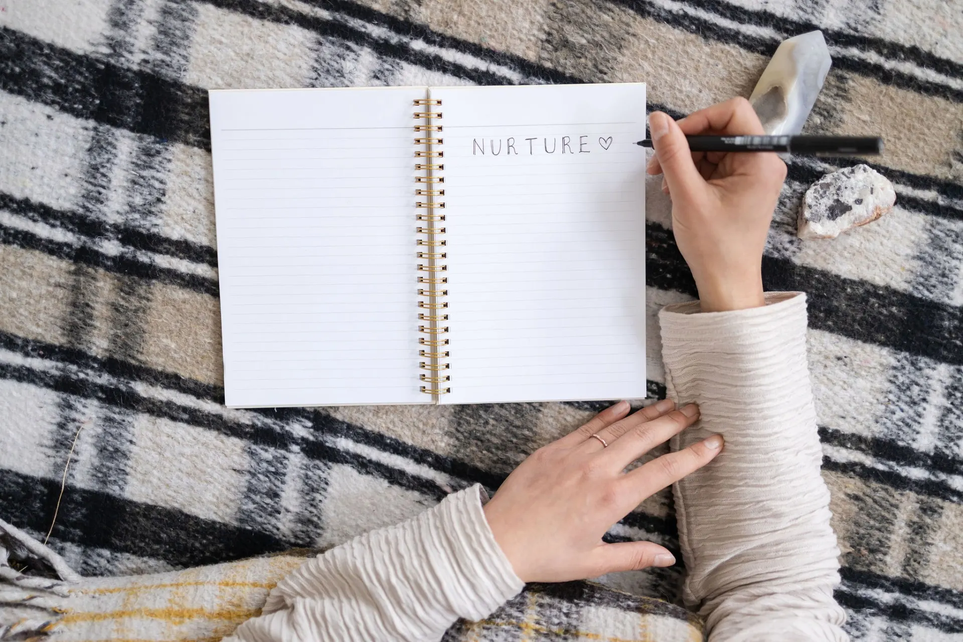 Hands writing in a journal on a woven blanket